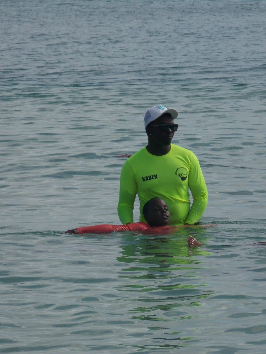 DSA instructor Kaden providing personalised 1-on-1 floating support to a young swimmer in the clear Caribbean sea, Barbados
