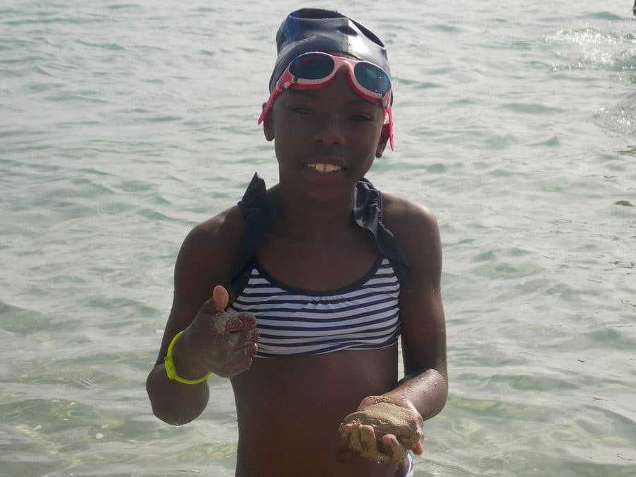 A young Don Shark Aquatics swimmer smiling in the shallows